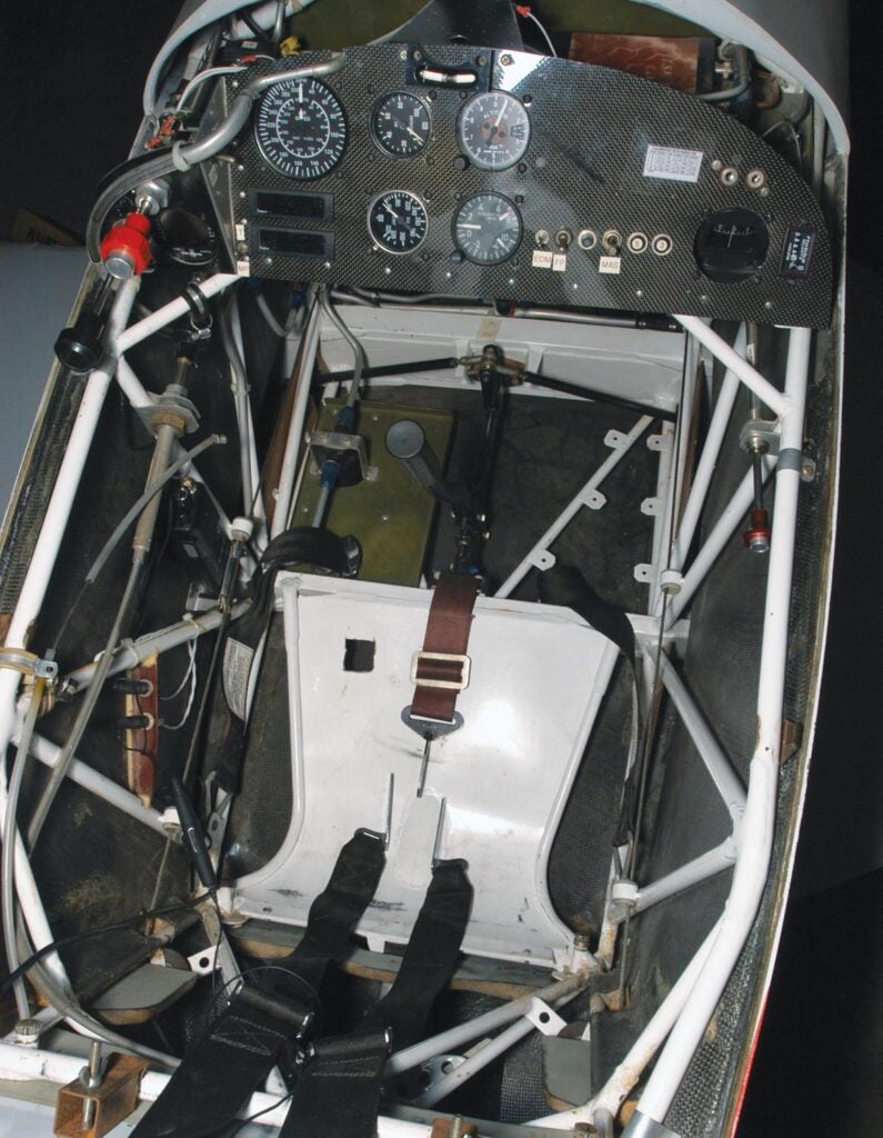 Befitting a dedicated racer, bare essentials mark Phantom’s compact cockpit; an EDM 700 engine monitor hiding under the throttle and mixture is the most sophisticated instrument and is used for data logging. Remnants of the Mong white-painted steel-truss fuselage easily stand out against the black carbon fiber skin. As with previous Aberle racers, Phantom uses a one-piece lift-off canopy. 