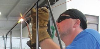 Aircraft welder using oxy-acetylene to weld an aircraft component.